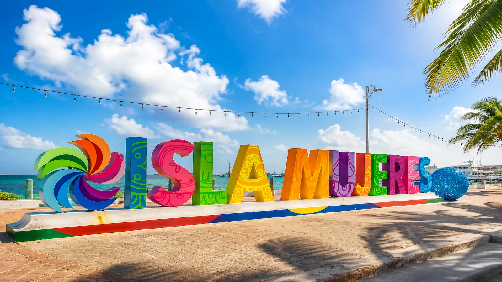 Colorful Isla Mujeres sign framed by palm trees