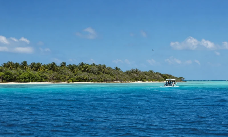 Boat approaching protected Isla Contoy across turquoise Caribbean water