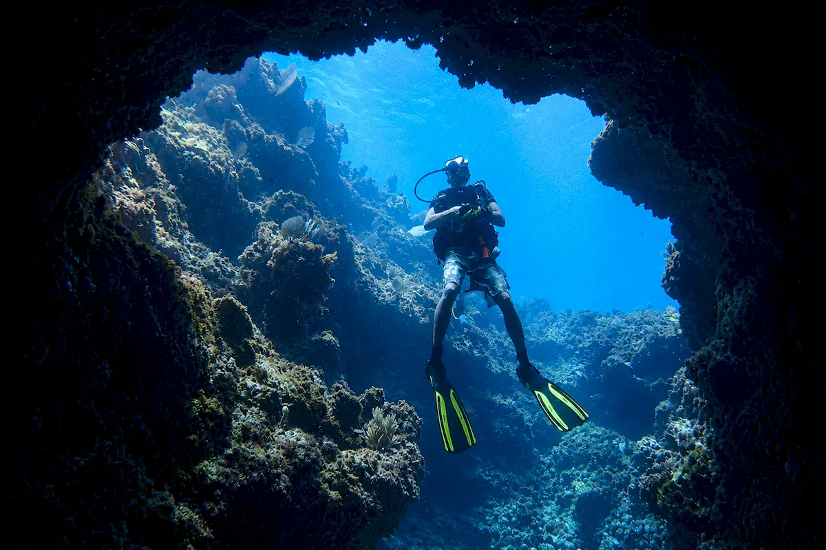 Scuba diver approaching an underwater rock formation