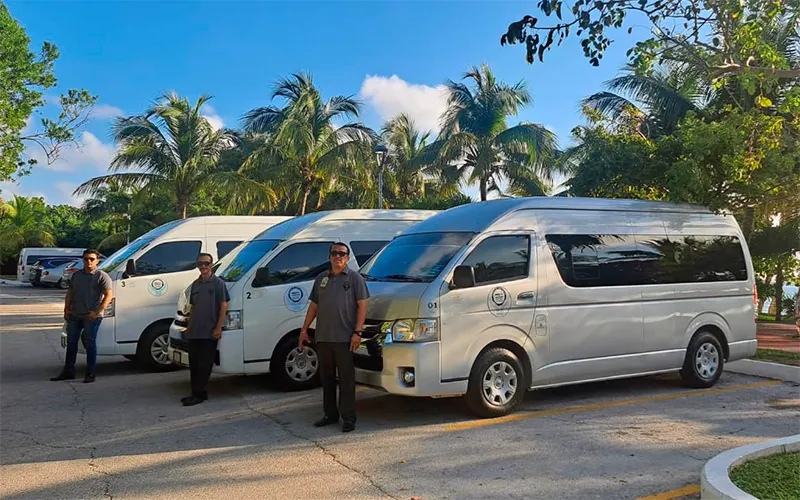 Héctor and the ground transportation team beside the passenger vans used for guest transfers